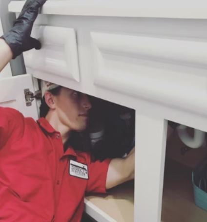 Direct Services plumber working under a kitchen sink
